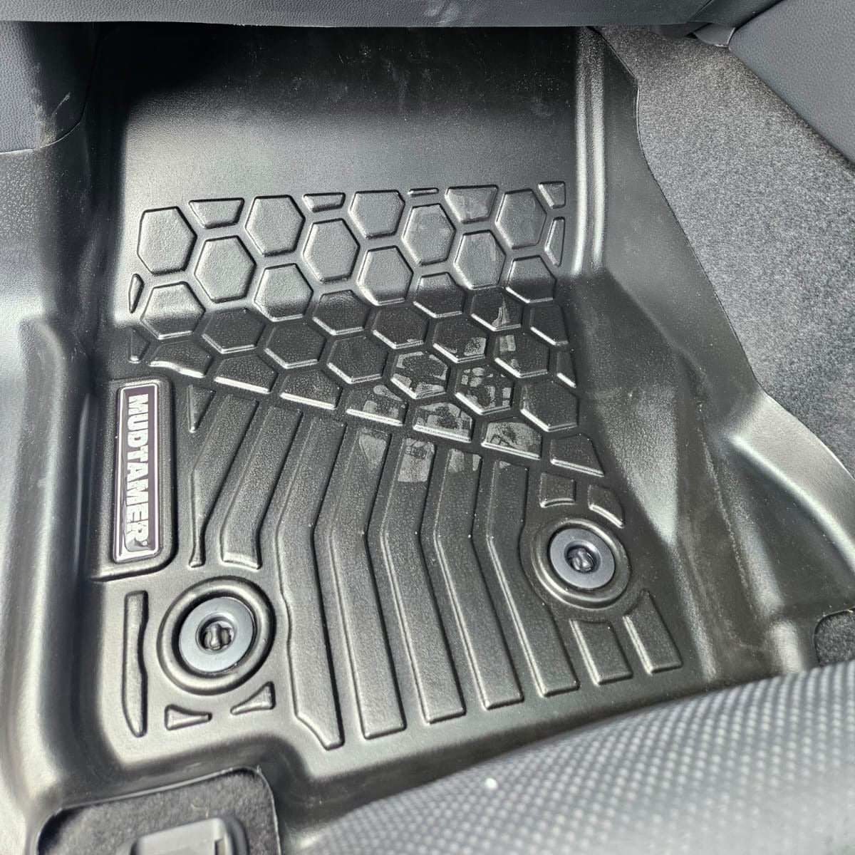 Car floor mat with tread pattern and brand logo on a car interior background