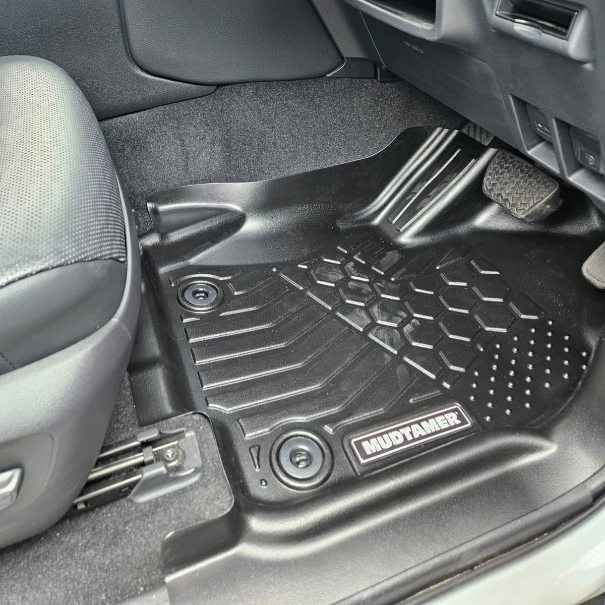 Car interior with black floor mats featuring a brand logo.
