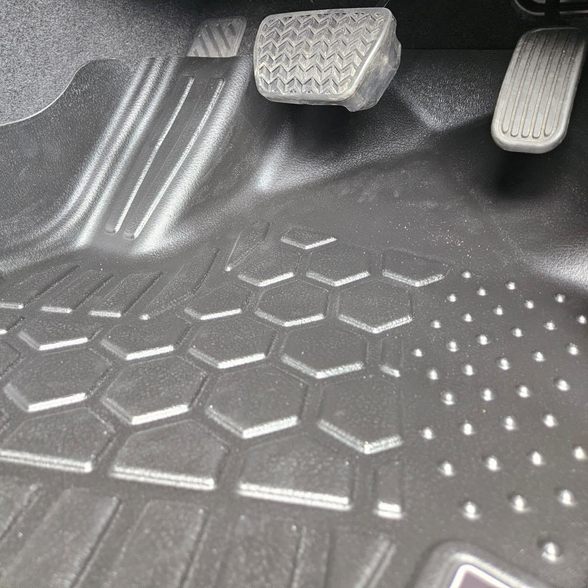 Car interior with a detailed view of the floor mat and pedals.